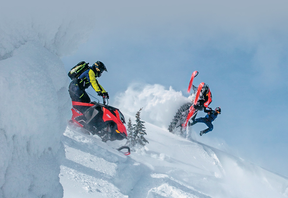 two people riding snowmobiles