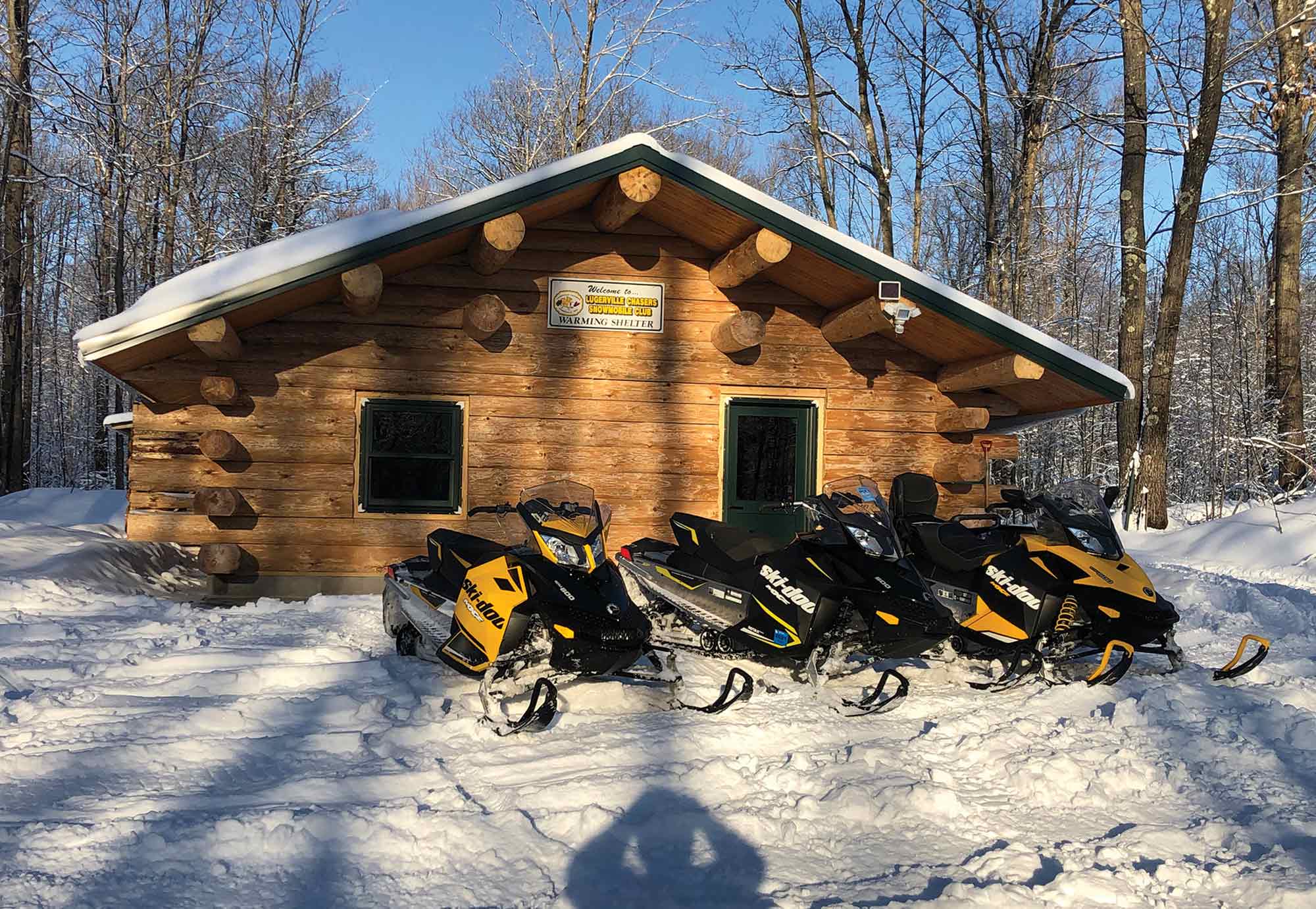 Snow Mobiles in front of a cabin in the snow