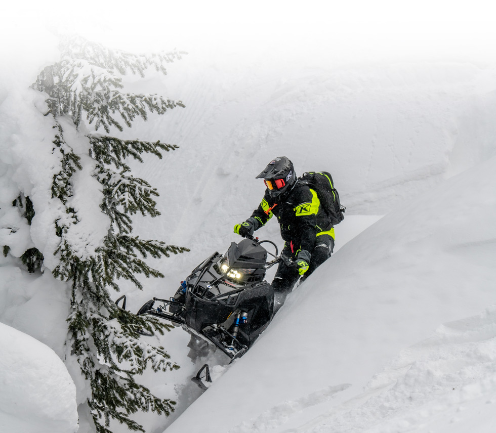 snowmobiler driving on a snowy hillside