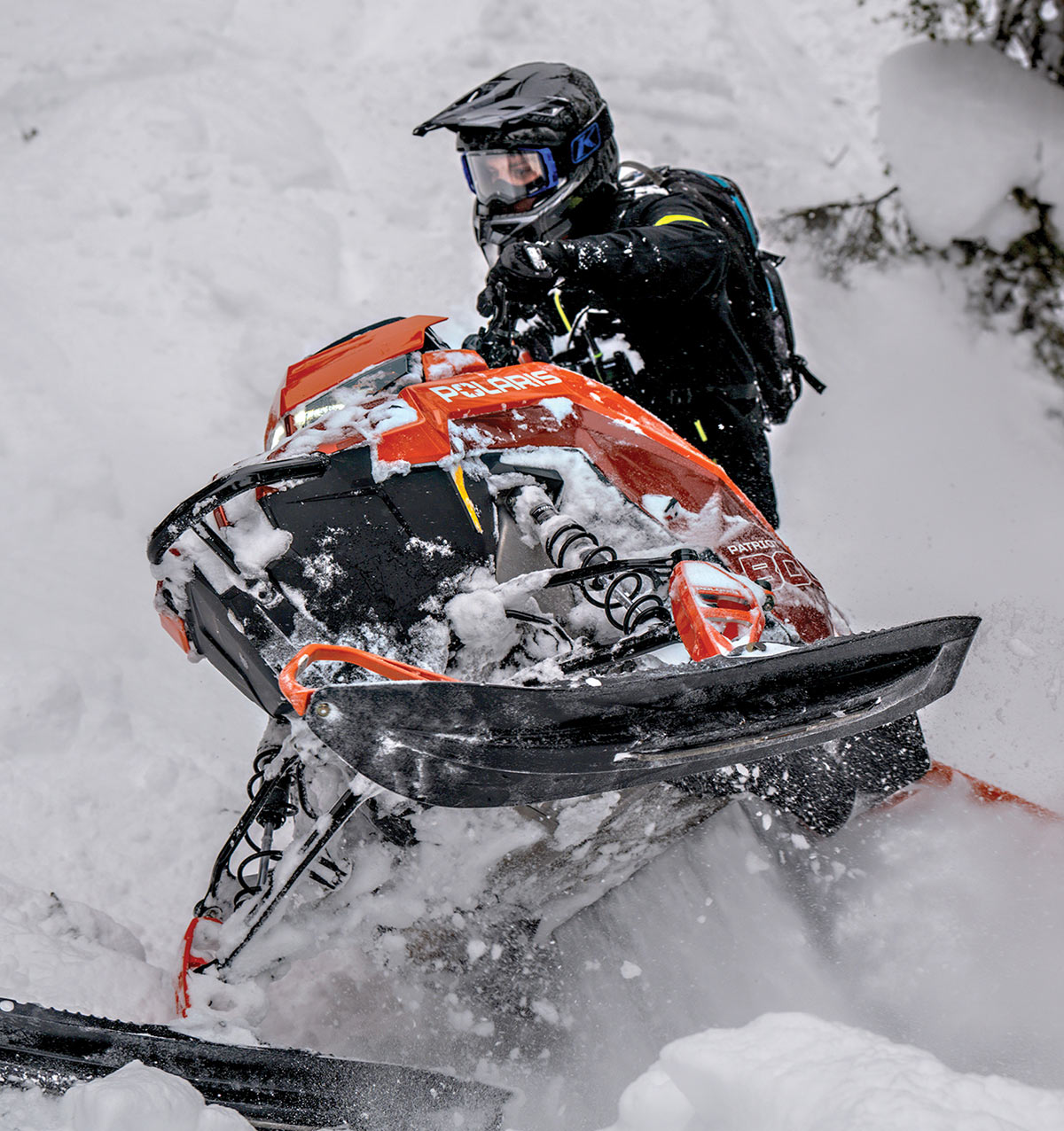 Rider on an orange Polaris in deep snow